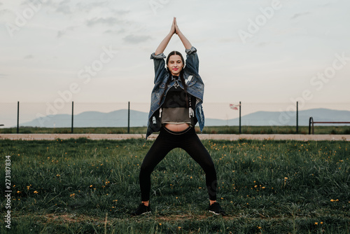 Pregnant woman is exercising outside. The concept of taking care of yourself during pregnancy. Training during pregnancy. An active mom expecting a baby.