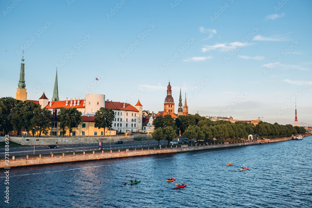 Naklejka premium Panoramic view of the Old Town from the cable-stayed bridge to the Daugava embankment at sunset. Riga, Latvia. Riga Castle with the Riga Cathedral in front of. St. Peter's Church in the background.