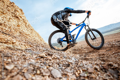 Professional well-equiped cyclist riding down on the rocky mountains. Concept of a freeride and off road cycling