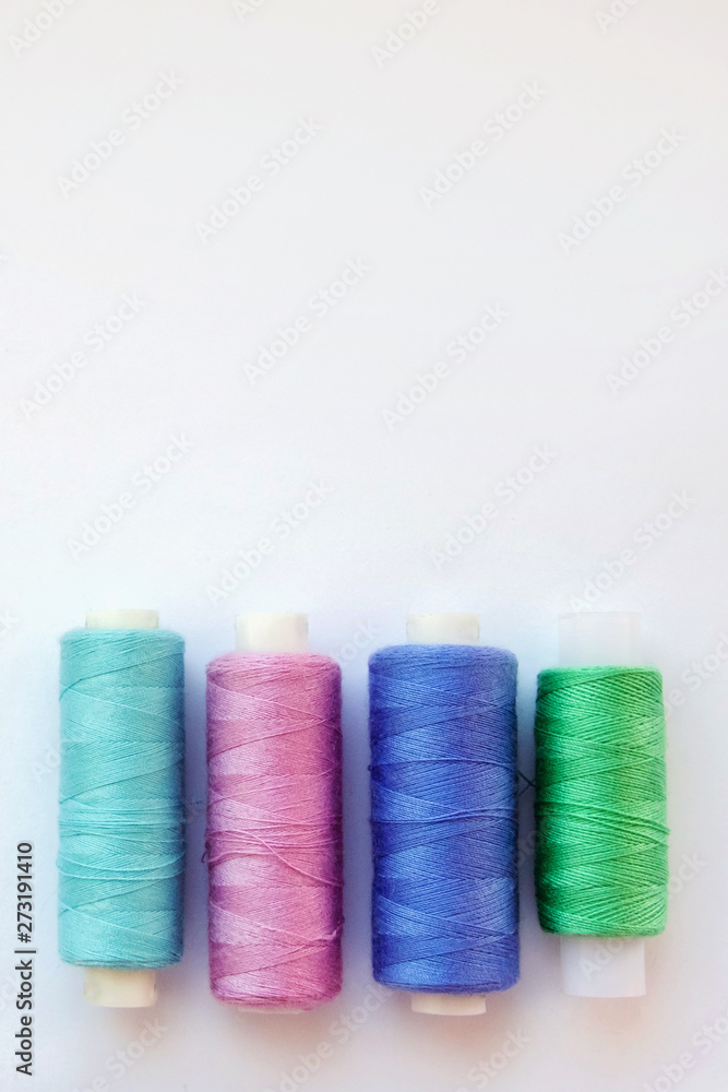 Multicolored thread coils on pink blue background. Sewing supplies and accessories for needlework, stitching, embroidery. space for text. flat lay, top view Multicolored thread coils on pink blue background. Sewing supplies and accessories for needlework, stitching, embroidery. space for text. flat lay, top view