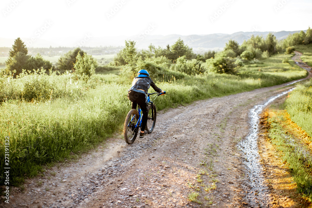 Professional well-equipped cyclist riding down on the mountain road during the sunset