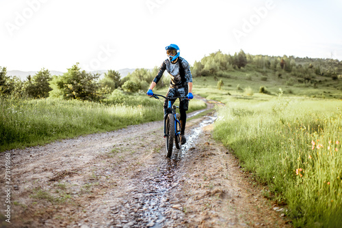 Professional well-equipped cyclist riding on the mountain road during the sunset