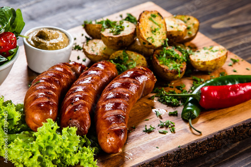 Grilled sausages and vegetables on cutting board photo