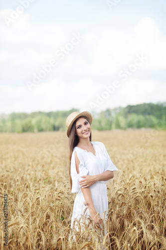 Beauty girl portrait in wheat field at sunset. Attractive young woman smiling and enjoying life. Beautiful brunette with a healthy long haircut. Wellness concept. Rich harvest Concept. 