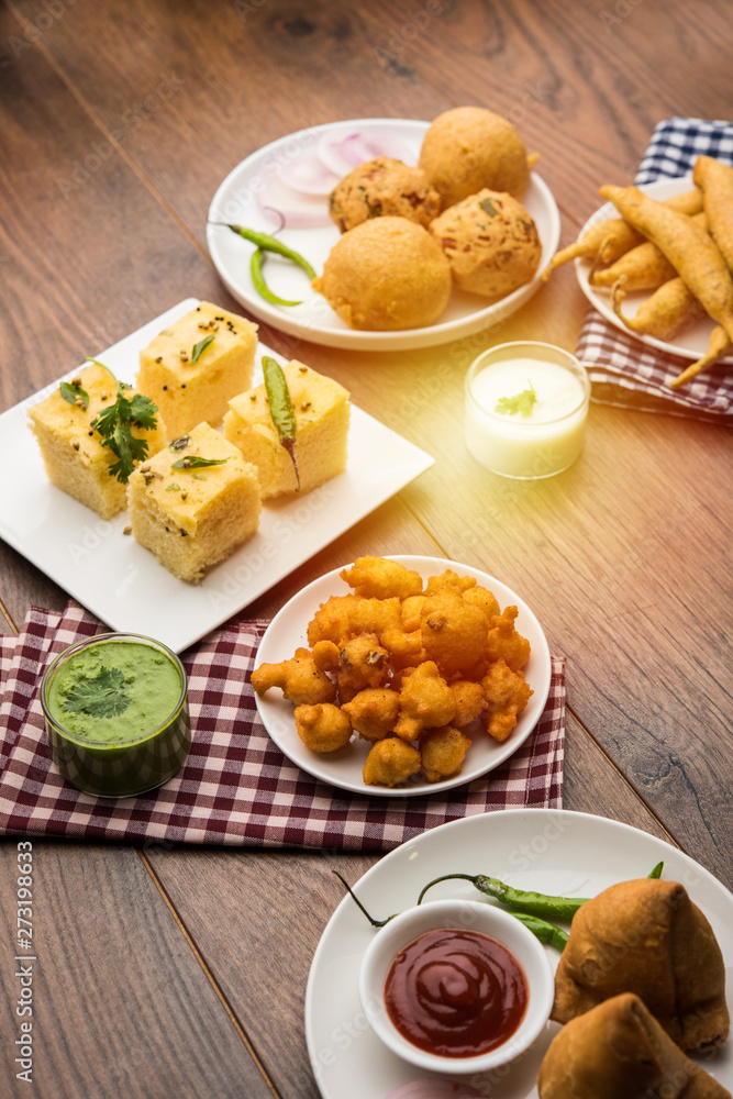 Indian Tea time snacks in group includes Veg Samosa, Kachori/kachaudi, aloo bonda, khaman dhokla, bread, onion,chilli and moong pakora/pakoda/bhaji/bhajji/Bhajiya/bajji with sauces, selective focus Indian Tea time snacks in group includes Veg Samosa, Kachori/kachaudi, aloo bonda, khaman dhokla, bread, onion,chilli and moong pakora/pakoda/bhaji/bhajji/Bhajiya/bajji with sauces, selective focus