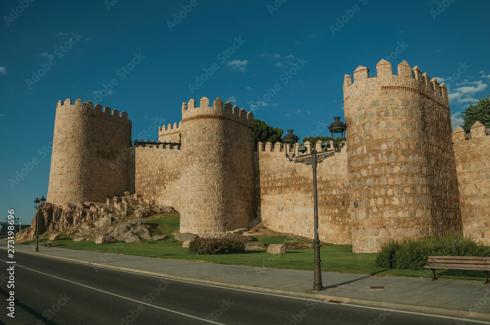 Street and light posts beside towers in the wall around Avila