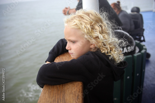 young girl looking out over water on ferry boat standing at railing
