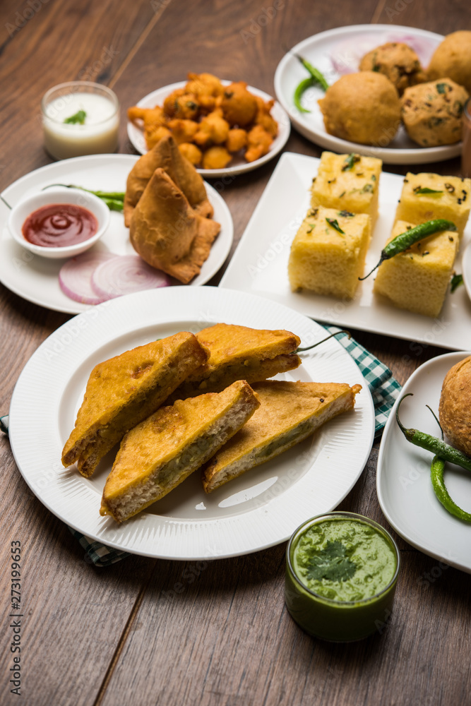 Indian Tea time snacks in group includes Veg Samosa, Kachori/kachaudi, aloo bonda, khaman dhokla, bread, onion,chilli and moong pakora/pakoda/bhaji/bhajji/Bhajiya/bajji with sauces, selective focus Indian Tea time snacks in group includes Veg Samosa, Kachori/kachaudi, aloo bonda, khaman dhokla, bread, onion,chilli and moong pakora/pakoda/bhaji/bhajji/Bhajiya/bajji with sauces, selective focus