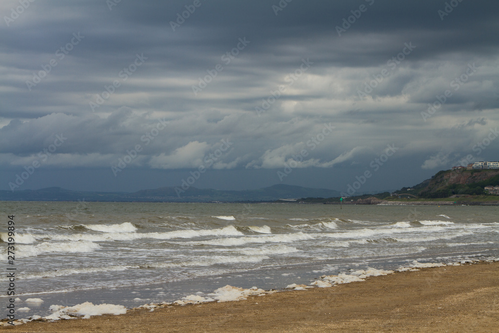 Heavy sea and cloudy sky from sandy beach in Wales