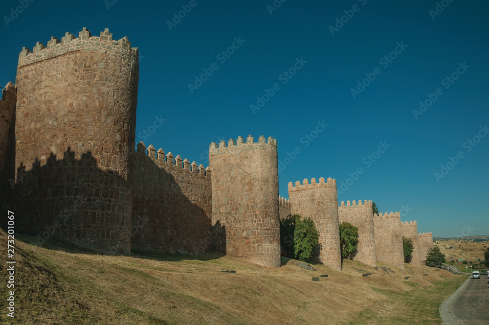 Stone towers on the large city wall next to street at Avila