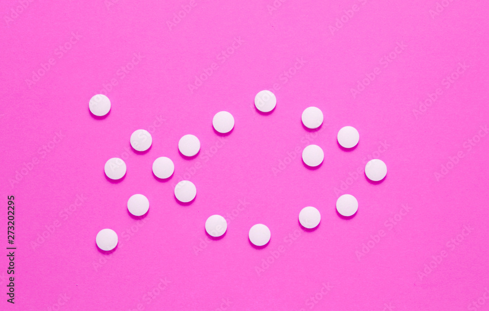 Form of fish laid out of white pills on pink background. Medical minimalistic concept, top view
