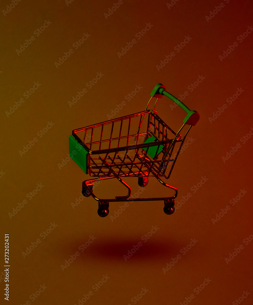 Minimalism shopping concept. Toy shopping trolley, neon night. Photo with shadow Minimalism shopping concept. Toy shopping trolley, neon night. Photo with shadow