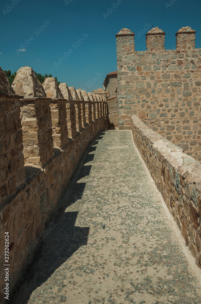 Pathway over thick stone wall with battlement around Avila