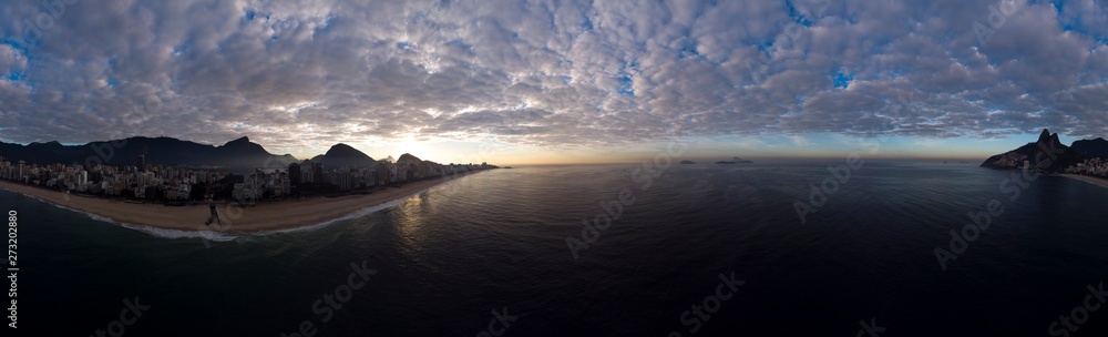 Sunrise 360 degree full panoramic aerial view of Rio de Janeiro with Ipanema beach in the foreground and the wider cityscape in the background with clouds lit up by the sun from below