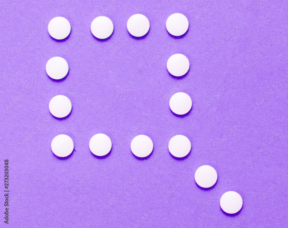 Minimalistic medical concept. A group of identical white tablets and one unique tablet on purple background. Top view Minimalistic medical concept. A group of identical white tablets and one unique tablet on purple background. Top view