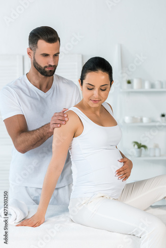 handsome bearded man standing near attractive pregnant woman in spa center