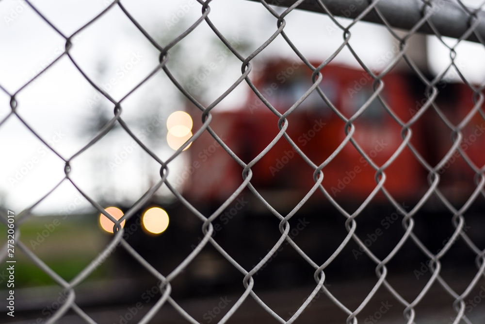 Fototapeta premium Closeup of chain link fence with freight train behind