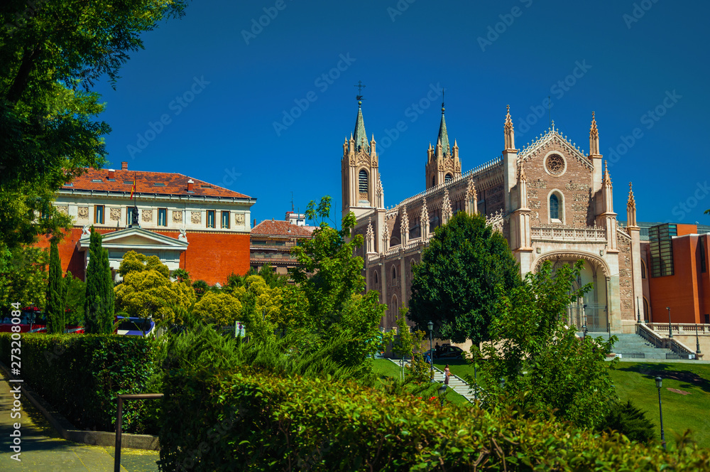 Leafy trees and lawn on garden in front of Cathedral in Madrid