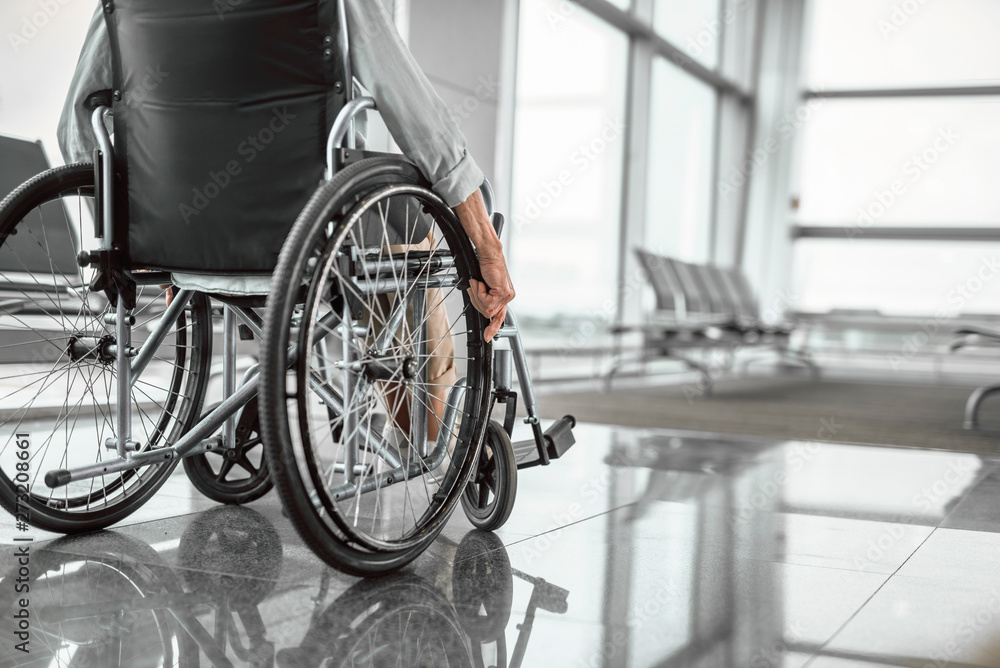 Elderly woman is using a wheelchair in front of the window Elderly woman is using a wheelchair in front of the window
