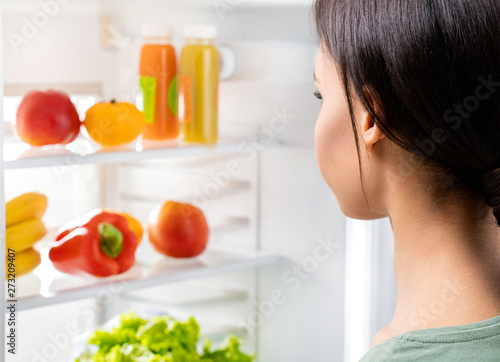 Young lady looking at fresh food in refrigerator
