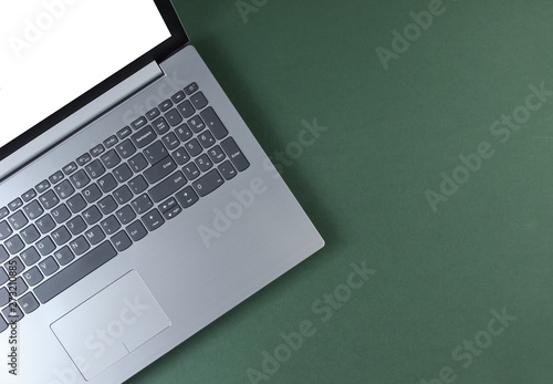 Fragment of laptop with a white screen on a green background. Top view