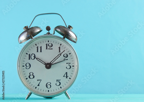 Retro alarm clock closeup on a blue background.