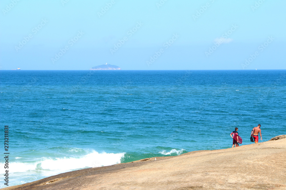 surfers walking on the stone by the sea surfers walking on the stone by the sea