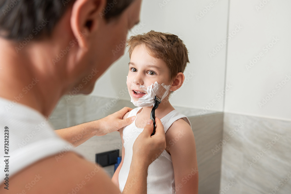 Father and son shaving together in bathroom at home