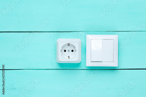 Power socket and switch on blue wooden wall, minimalism