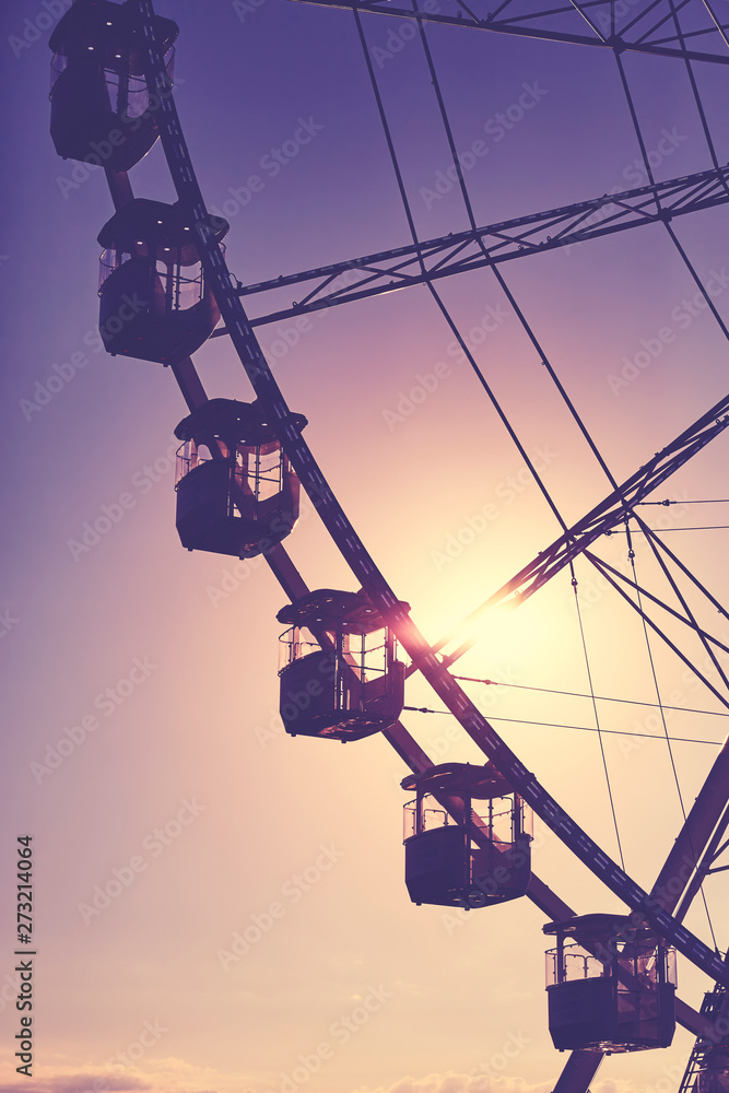 Silhouette of a Ferris wheel at sunset, color toning applied.