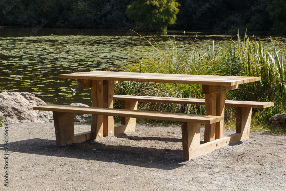 Wooden picnic table near a lake in a park Wooden picnic table near a lake in a park