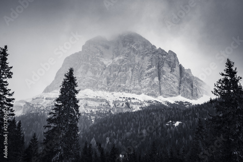 dramatic black and white foggy snowcapped peaks mountain range in dolomites in wintertime, giau pass, italy