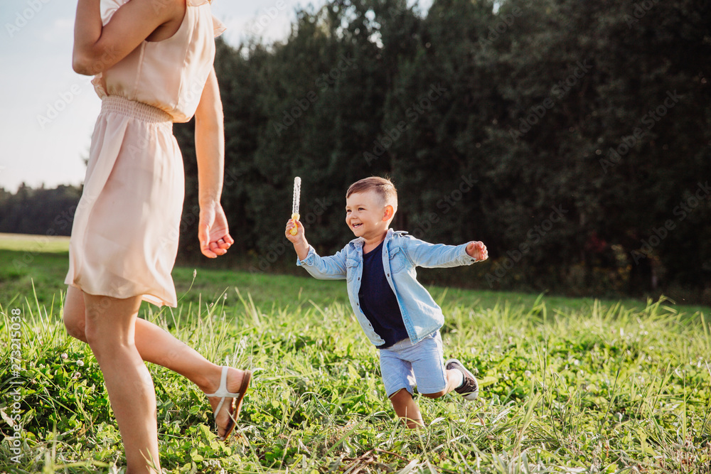 Fototapeta premium Happy mother with little son playing together in field in summer day