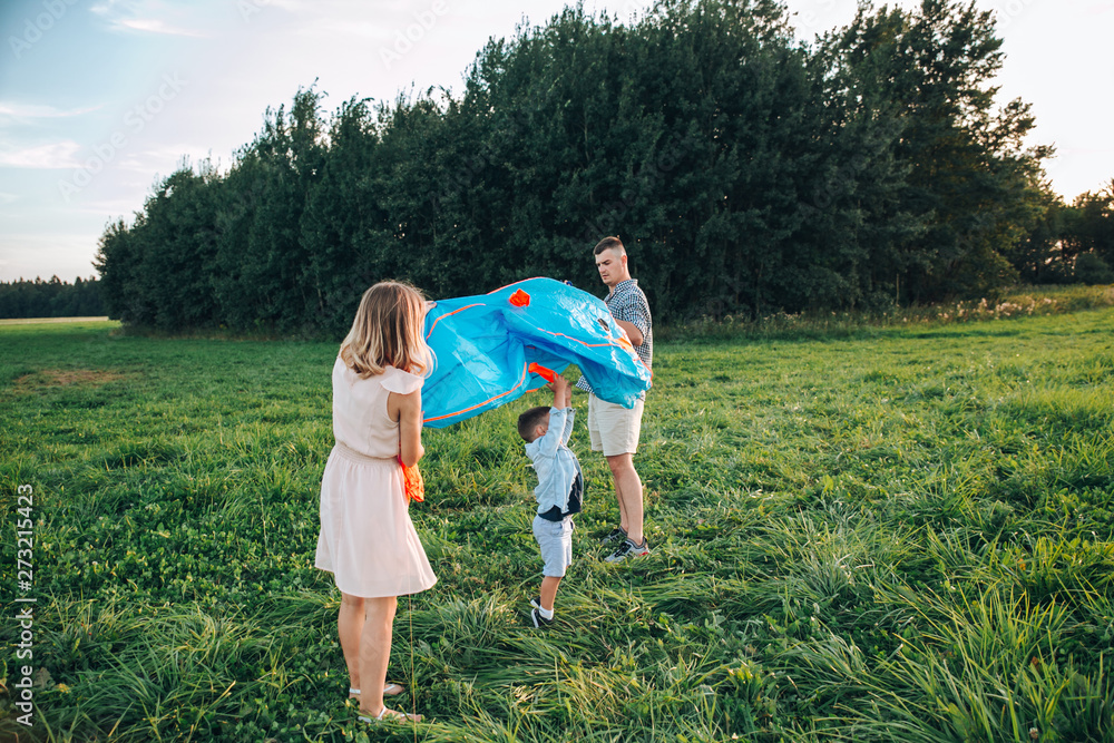 Happy family father, mother and child son launch a kite on meadow at sunset Happy family father, mother and child son launch a kite on meadow at sunset
