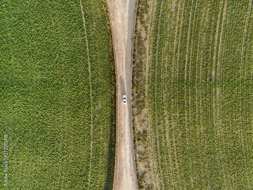 Aerial view of a car driving in between two agricultural circles in the middle of the Saih Al Salam Desert in Dubai, U.A.E.