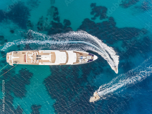 Aerial view of jet ski driving around luxurious yacht in the mediterranean sea, Mikonos island, Greece.
