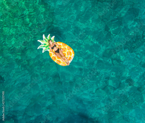 Aerial view of woman floating in inflatable pineapple on Atokos island, Greece. photo