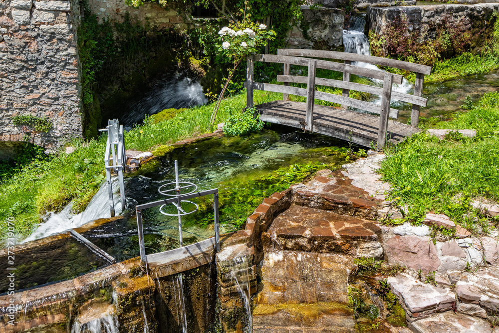 The small village of Rasiglia, crossed by many streams and waterfalls, fed by the Menotre river. A sluice regulates the flow of water. A wooden bridge. Old brick houses. Foligno, Umbria. The small village of Rasiglia, crossed by many streams and waterfalls, fed by the Menotre river. A sluice regulates the flow of water. A wooden bridge. Old brick houses. Foligno, Umbria.