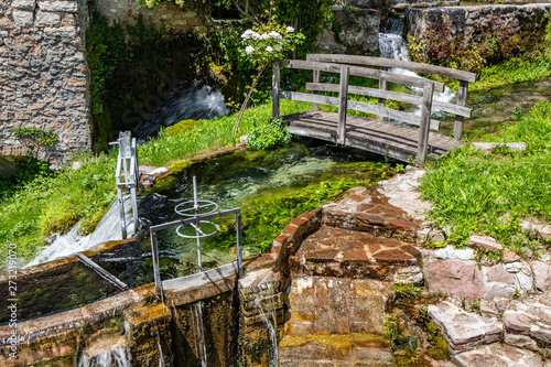The small village of Rasiglia, crossed by many streams and waterfalls, fed by the Menotre river. A sluice regulates the flow of water. A wooden bridge. Old brick houses. Foligno, Umbria.