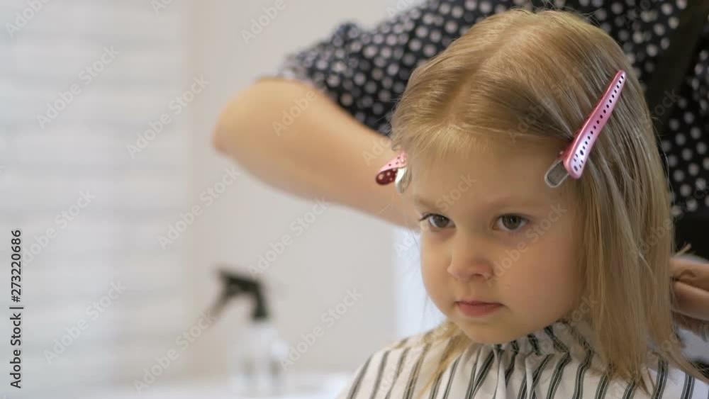 Stylist hairdresser makes a hairstyle for a cute little girl in a beauty salon. Hairdressing, hair cutting. Stylist hairdresser makes a hairstyle for a cute little girl in a beauty salon. Hairdressing, hair cutting.