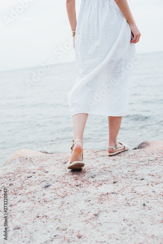 cropped view of woman in white dress and sandals standing near sea © LIGHTFIELD STUDIOS
