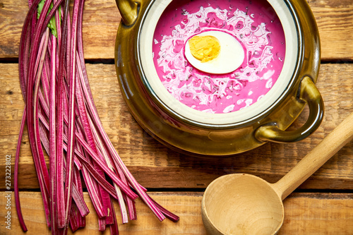 Old vase with  cold beetroot soup and spoon on rustic wooden table photo