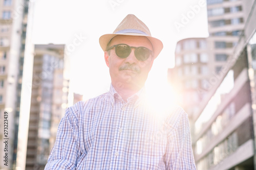 Retired senior hispanic man with hat and summer glasses standing and smiling at sunny day. © Viktor Koldunov