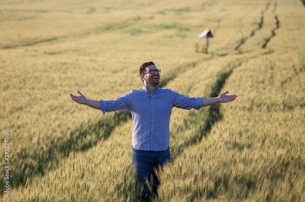 Happy farmer with raised arms in barley field