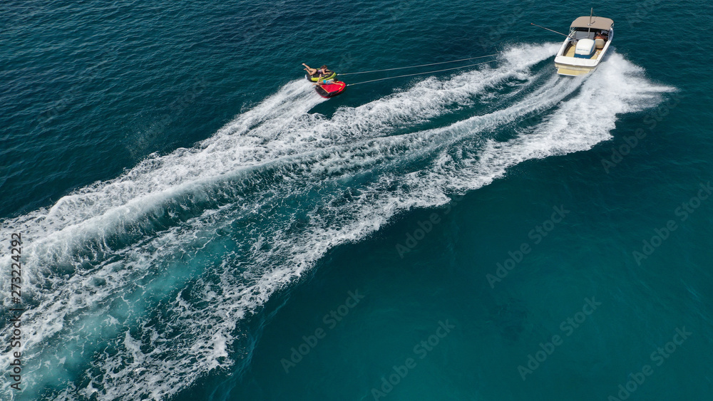 Aerial photo of extreme powerboat donut watersports crusing in high speed in tropical turquoise bay Aerial photo of extreme powerboat donut watersports crusing in high speed in tropical turquoise bay