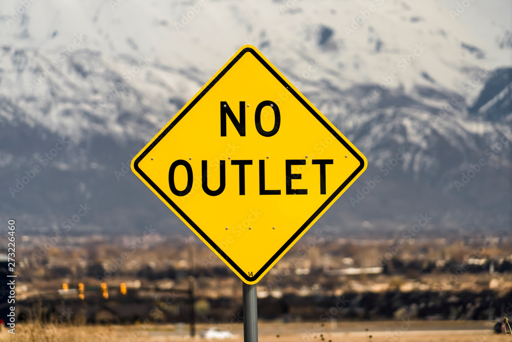 Close up view of a bright yellow and black No Outlet road sign