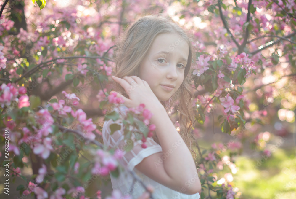teen girl near the blossoming apple trees in sun rays