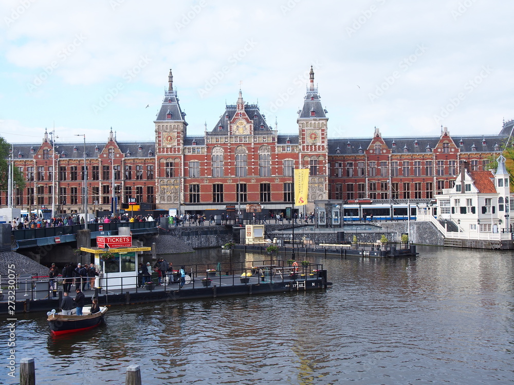 a scenery of amsterdam (central station, canal, trams and pier)