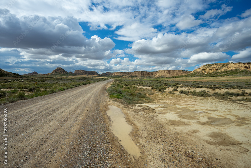 une route dans un paysage désertique avec des montagnes au fond