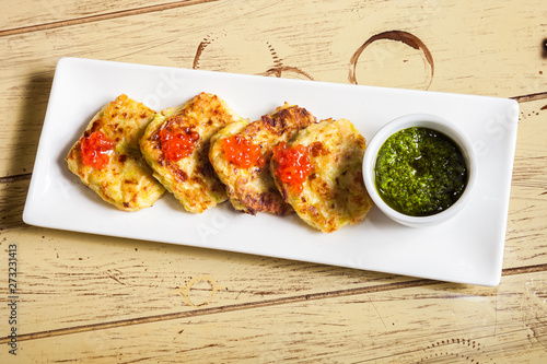 plate with potato pancakes, red caviar and pesto on wooden table